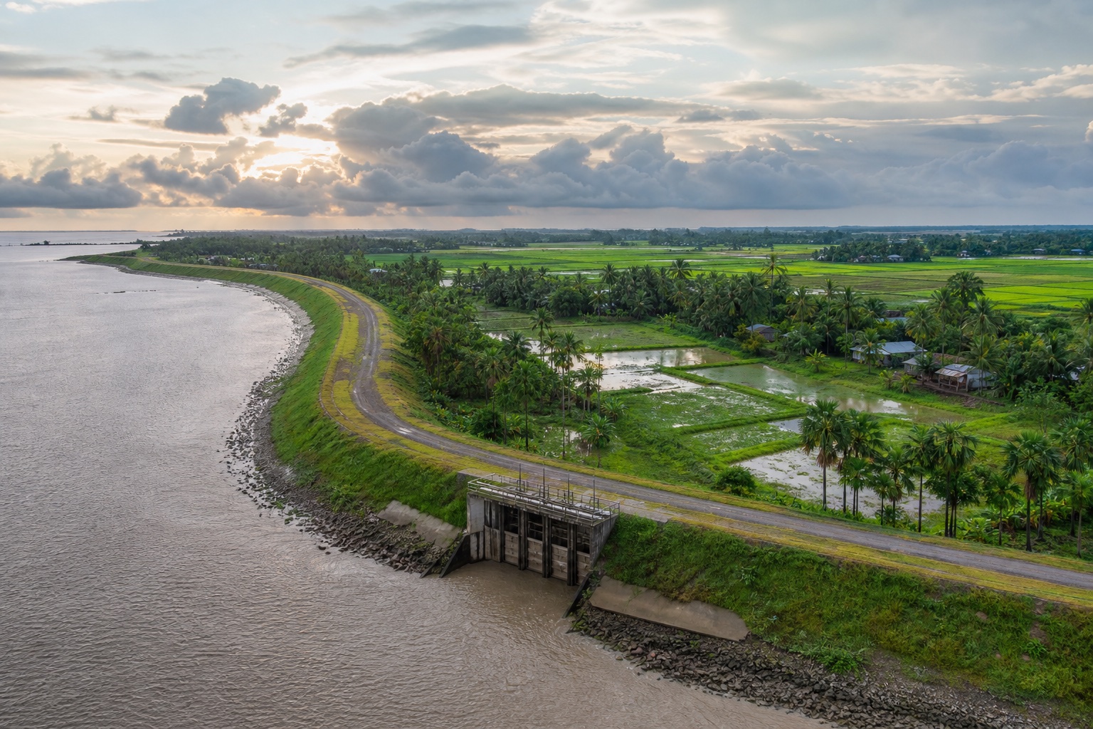 Representative coastal polder landscape with an embankment, tidal water, protected farmland and a drainage regulator